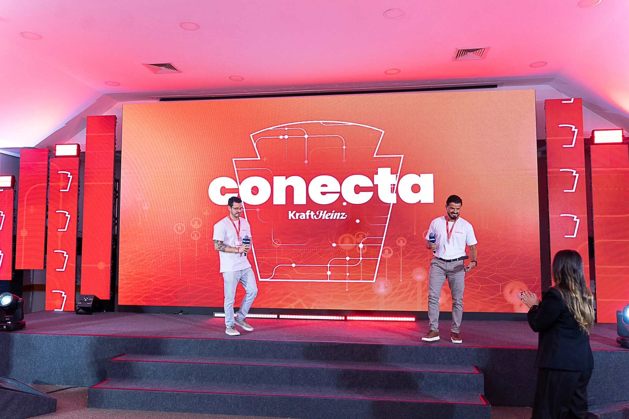 Apresentadores no palco vermelho da convenção Conecta Kraft Heinz