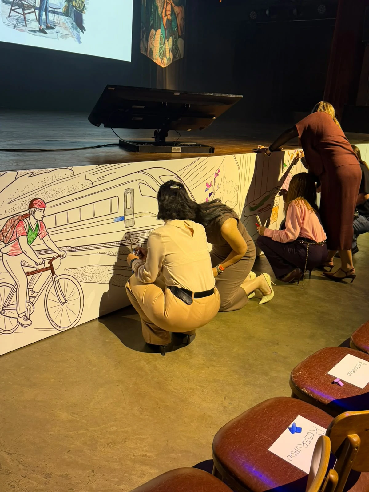 Convidados participam da pintura do painel artístico na frente do palco do Madart