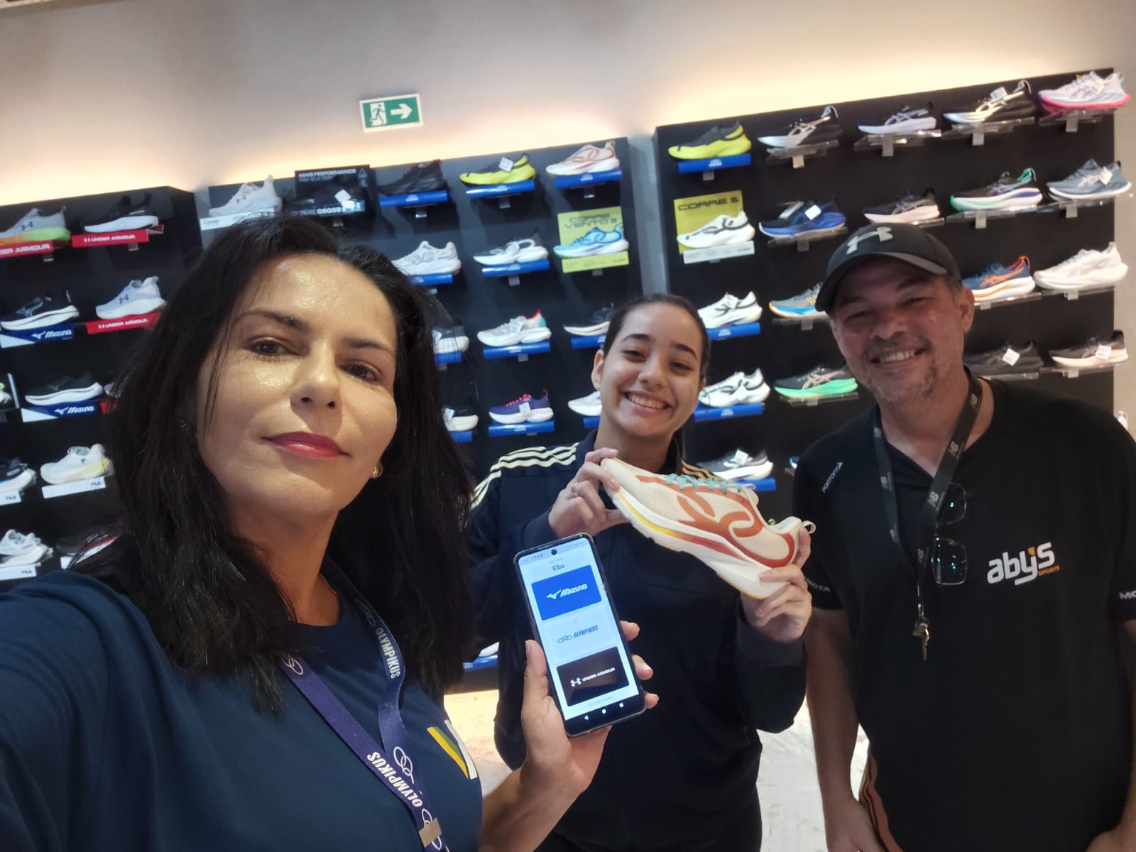 Pessoas apresentam um tênis diante de uma exposição de calçados no ponto de venda
